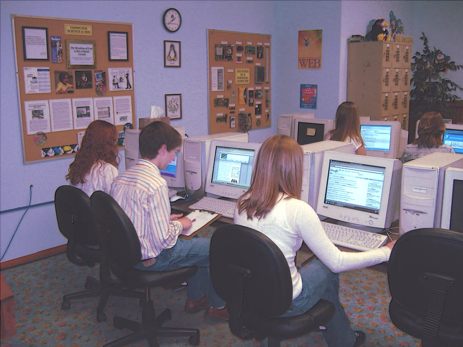 Students sitting in a classroom doing schoolwork on computers.